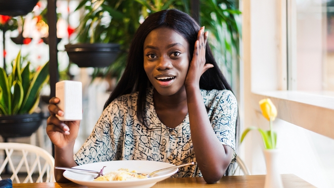 Une femme qui sale son plat au restaurant