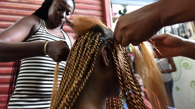 Une femme se fait tresser les cheveux dans un salon de coiffure au marché de Treicheville