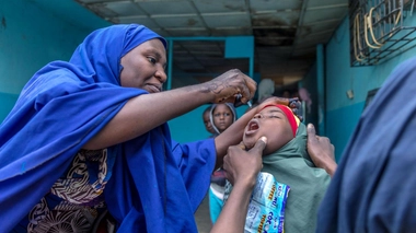 Un vaccinateur fournit à une jeune fille un vaccin oral contre la polio dans l'État de Kano, au Nigeria, en 2020