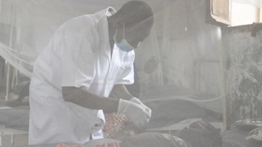 Un infirmier s'occupe d'un jeune patient malade de la rougeole, hôpital général de Bosobolo, en RDC, février 2021