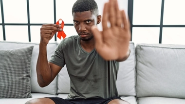 Un jeune homme tenant un ruban rouge, symbole de la lutte contre le sida