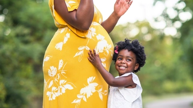 Une petite fille touchant le ventre d'une femme enceinte