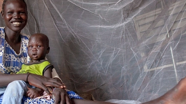 Une mère et son bébé de neuf mois sont assis sous une moustiquaire fournie par l'UNICEF dans l'État du Nil supérieur, au Soudan du Sud