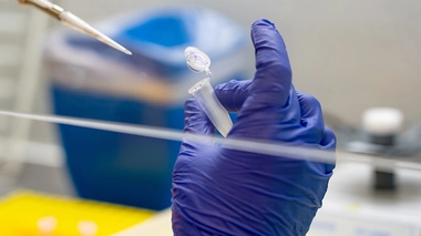 Un scientifique qui met un échantillon dans un flacon pour une analyse ADN