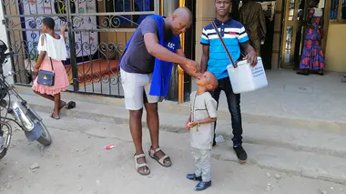 Des agents de santé administrent une dose de vaccin contre la polio à un enfant sur le parvis d'une église togolaise