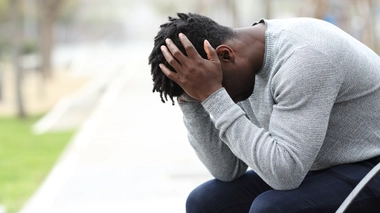 Un homme se tient la tête entre les mains en raison de céphalées